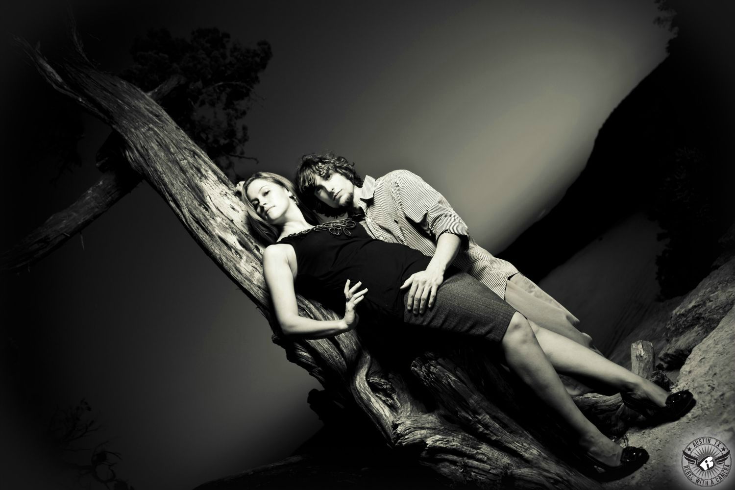 wavy haired brunette girl in a pink large weave sweater kisses a guy with dark short hair wearing a green long sleeve shirt while standing in fluffy sunlit brush with the sun warming the background in this Nicholas Sparks inspired engagement photograph in Austin.